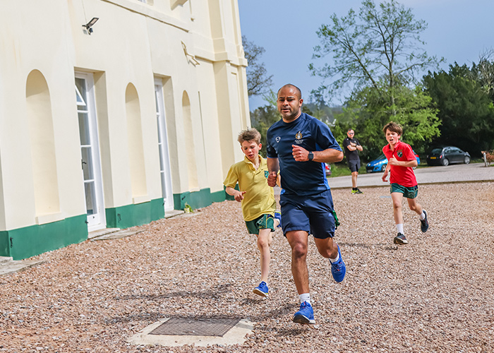 Two students running along with their teacher on sports day