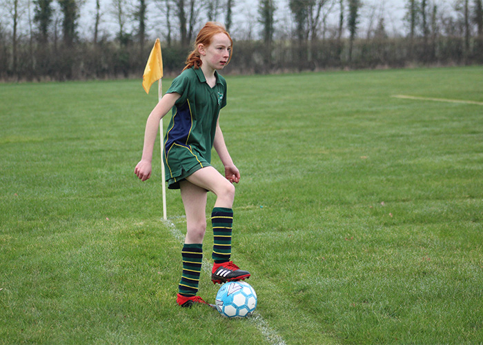 Action shot of a girl about to kick a football to her team mates