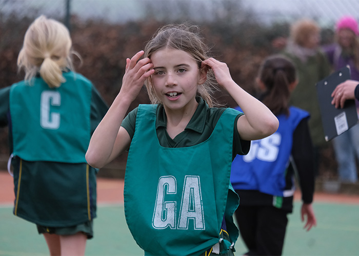A student in her sports bib playing netball
