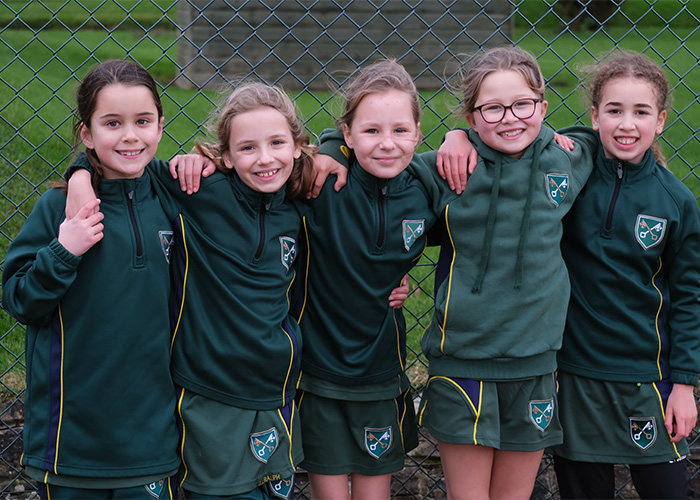 A girls sports team posing in their sports kit on the netball court