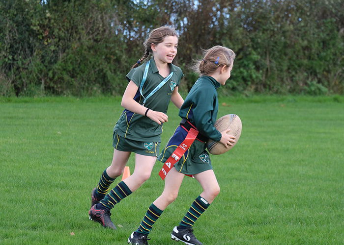 Two girls mid rugby game one with the ball