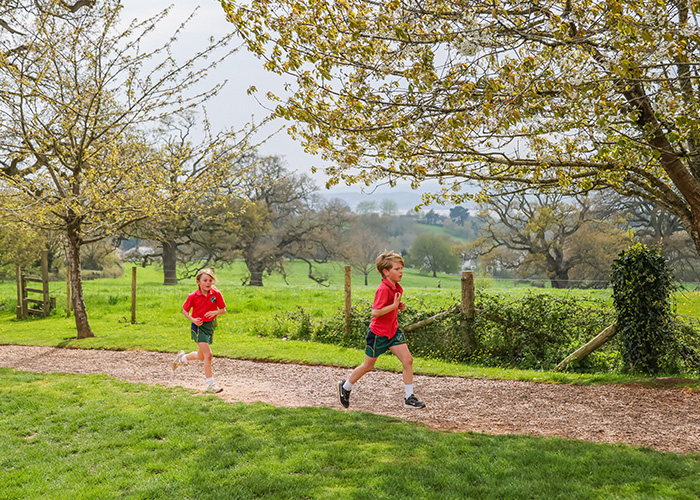A couple of students running on the school grounds in the summer time