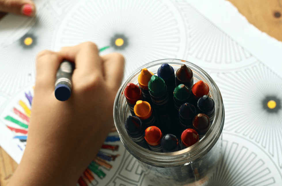 A pot of crayons with a child drawing