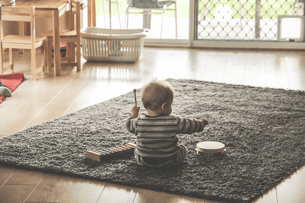 A picture of a baby on a rug with some musical instruments