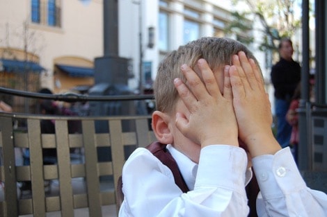 A tired child with their hands over their face