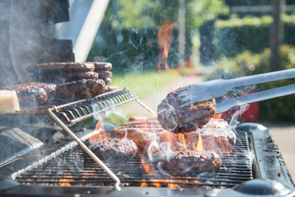 Burgers being turned on a BBQ