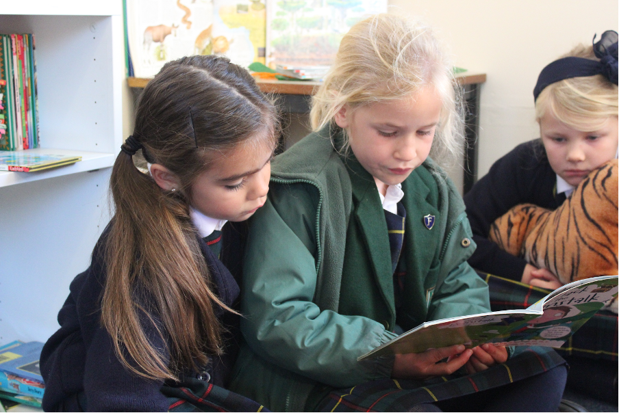 Two girls reading a book together