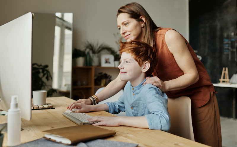 A mother helping her son use a computer