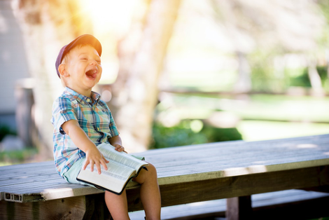 A little boy laughing with a book on his lap