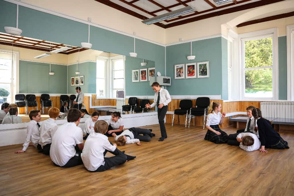 A boy standing up in a drama class at school performing