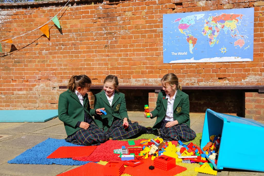 Three children sitting on the floor playing with toys