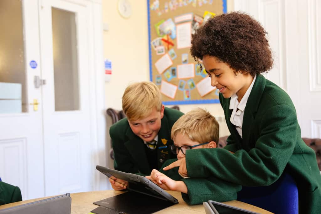 3 children on a tablet at school