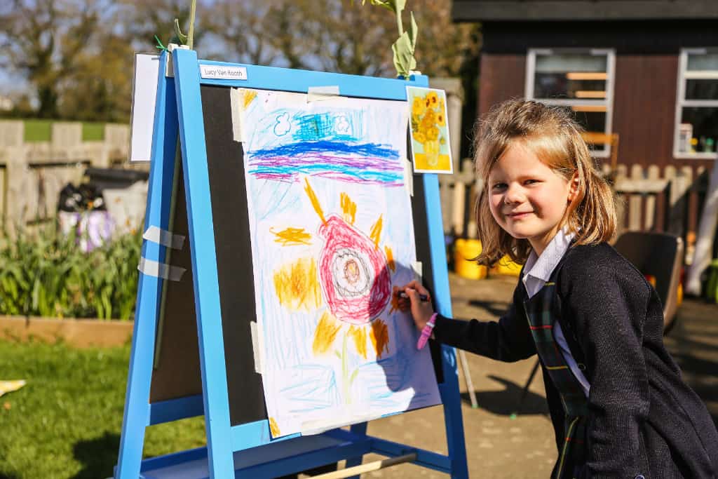 a girl doing art work on a canvas at school