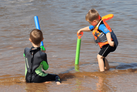 Two young siblings playing at the beach together