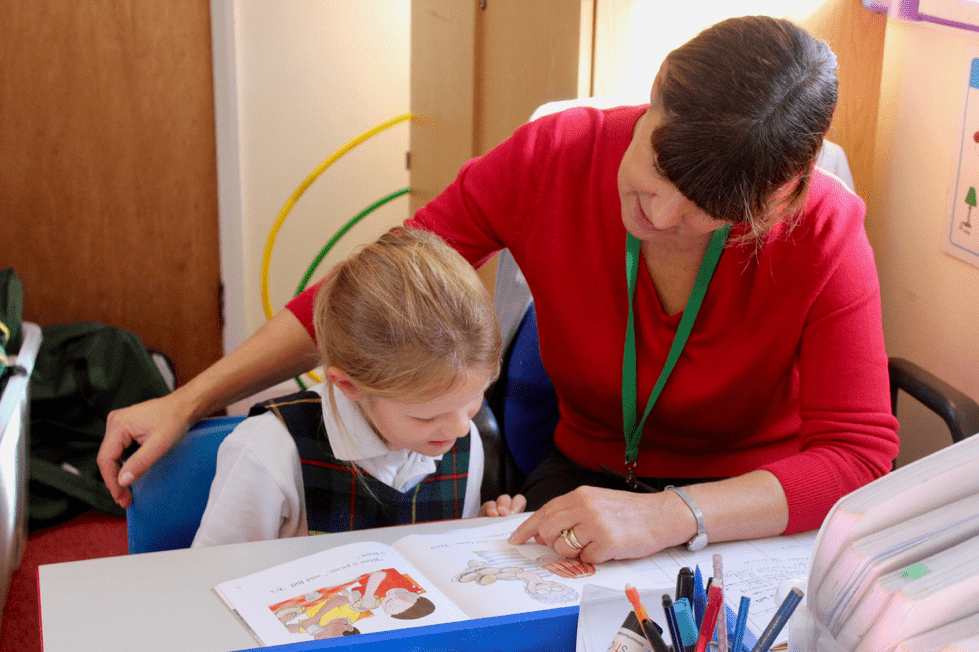 An HLTA helping a child read.