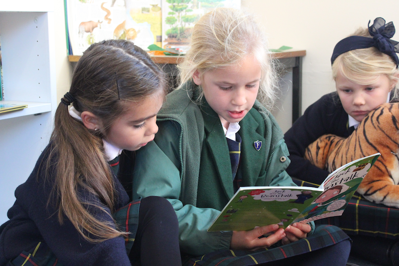 Three children sitting on the floor reading together