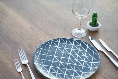 A wooden table with plates and cutlery laid out.