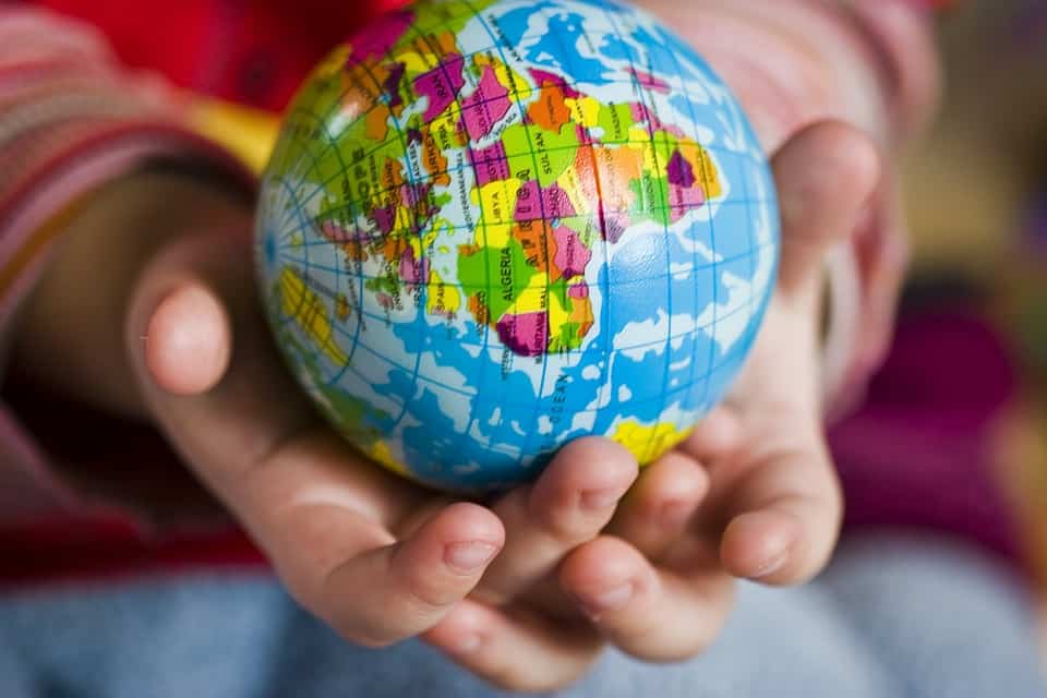 A child holding a tennis ball-sized world globe.