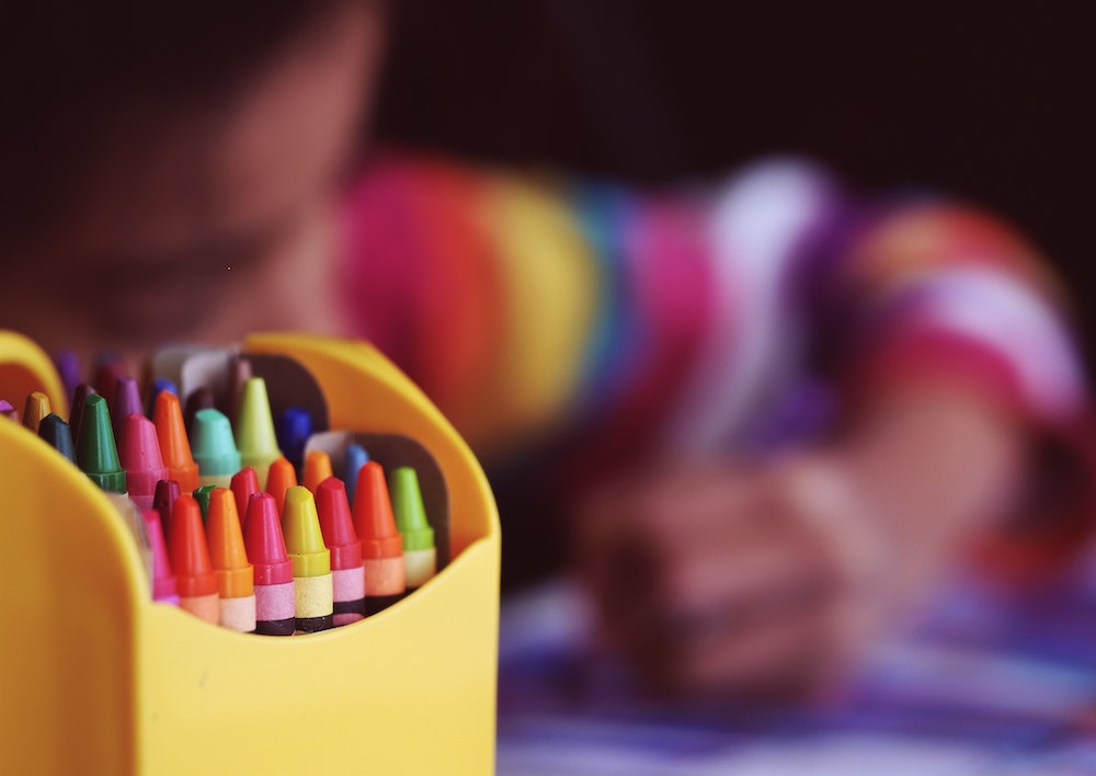 A child colouring using crayons