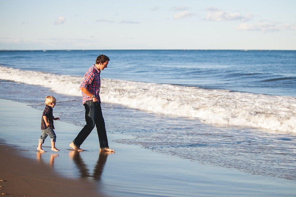 A father walking on the beach with his child