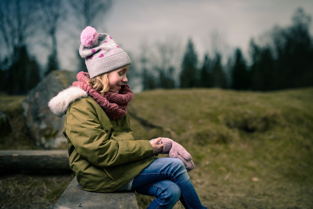 A girl wearing winter clothes including a hat and mittens