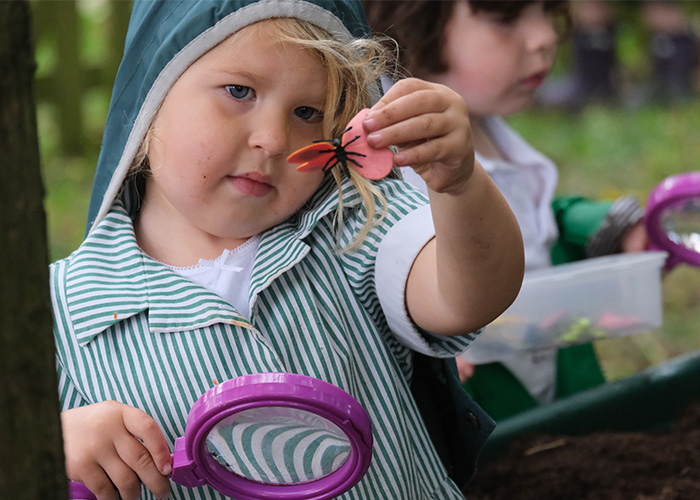 A young student showing a butterfly toy to the camera