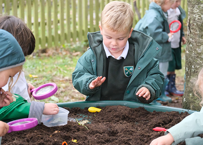 A young student playing in some mud