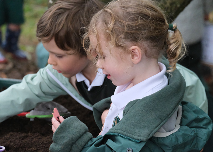 A young student playing in some mud