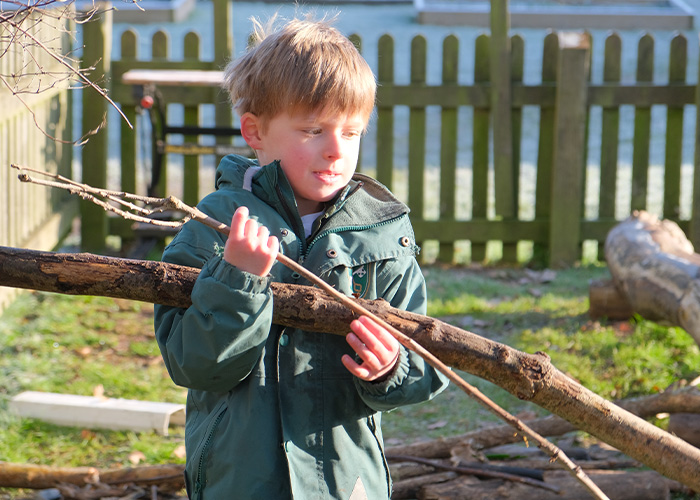A student during outdoor learning carrying some sticks