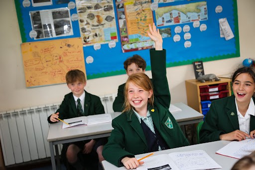 A student raising her hand in a classroom