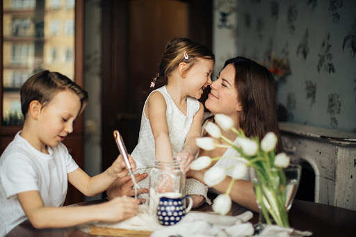 A mother sitting at a table with her two children