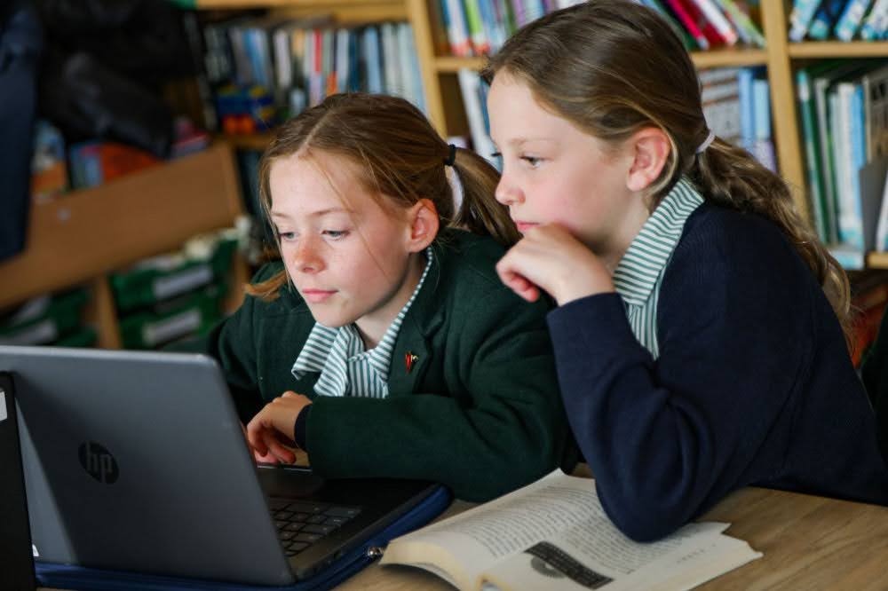 Two school students looking at a laptop screen