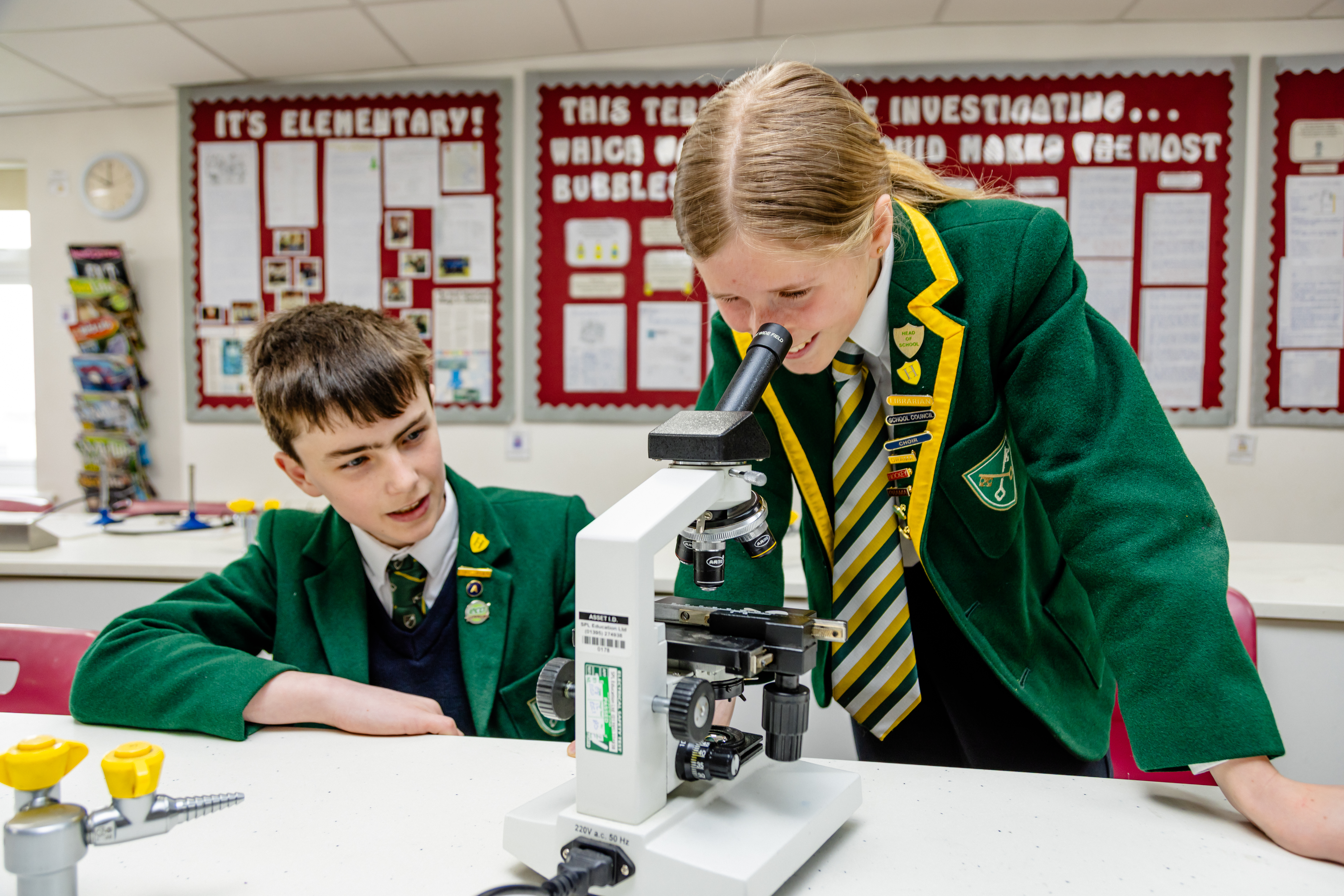 Two students using a microscope during their science lesson.